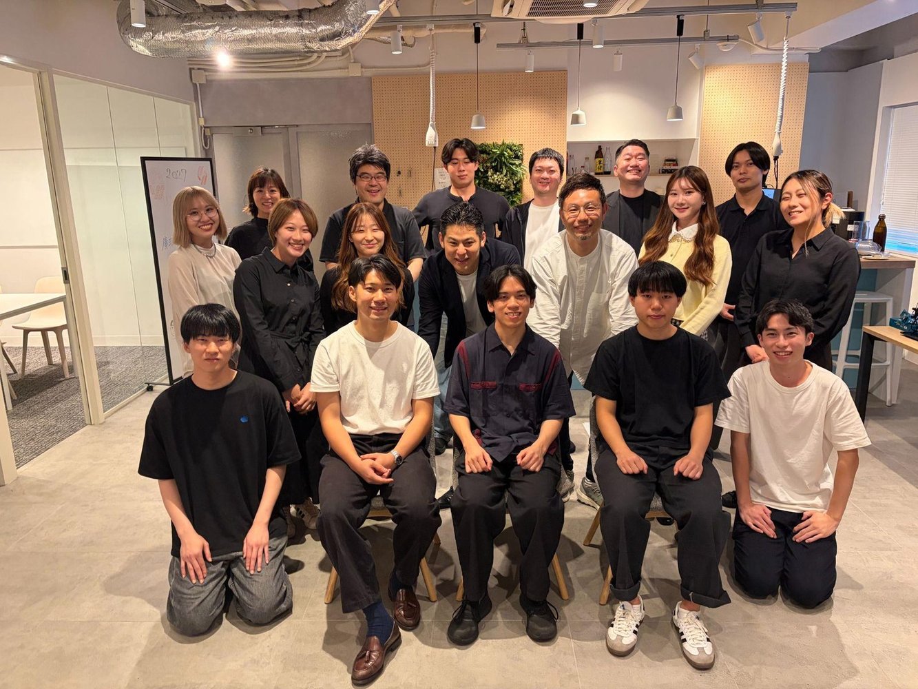 27卒 内定式の集合写真。内定者と社員が本社オフィスに集まり笑顔で並んでいる