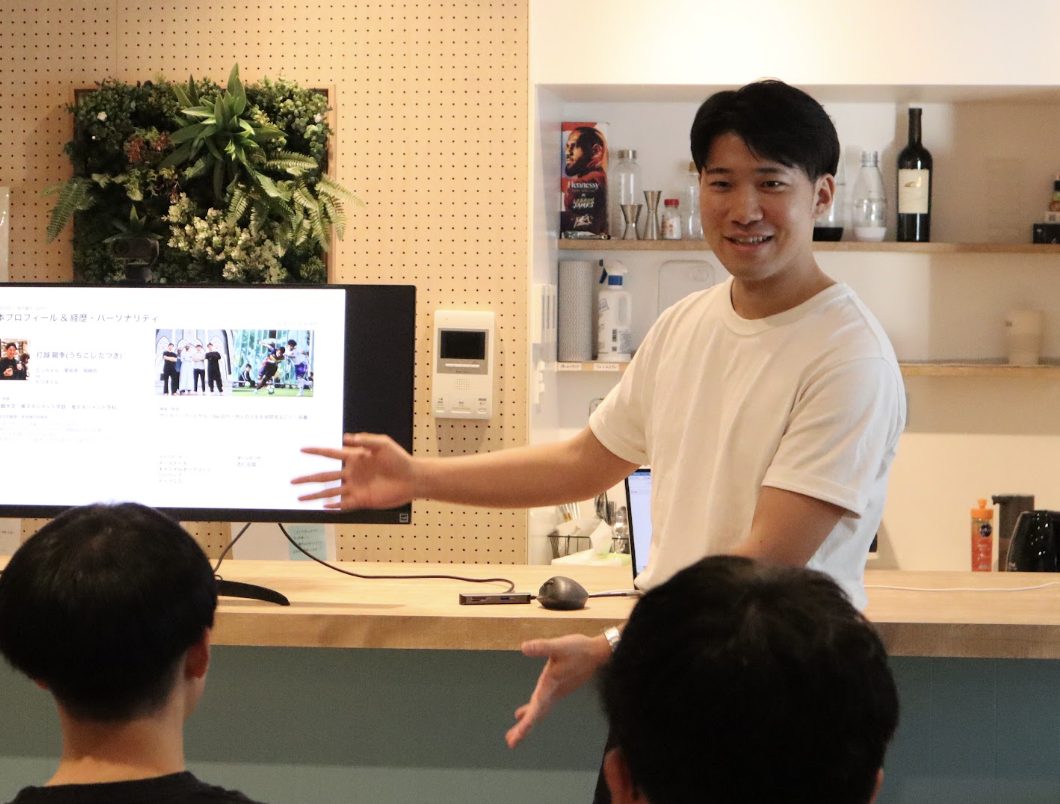 笑顔でスライドを指しながら発表する内定者